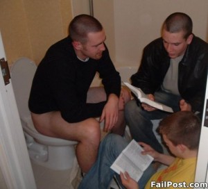 several guys in bathroom with one guy on toilet