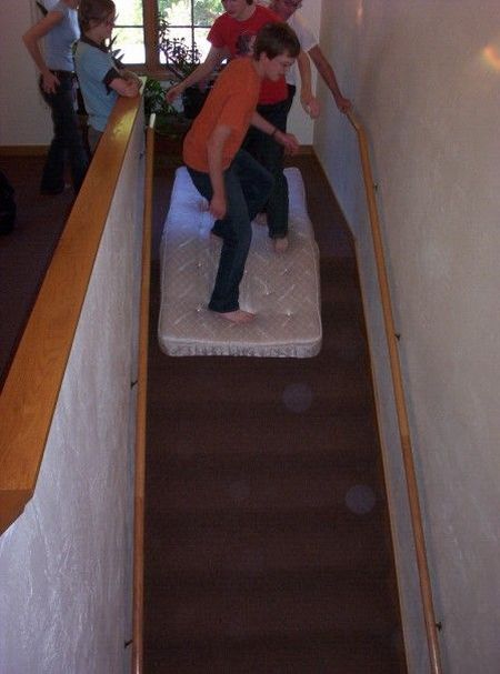 kids riding mattress down stairs
